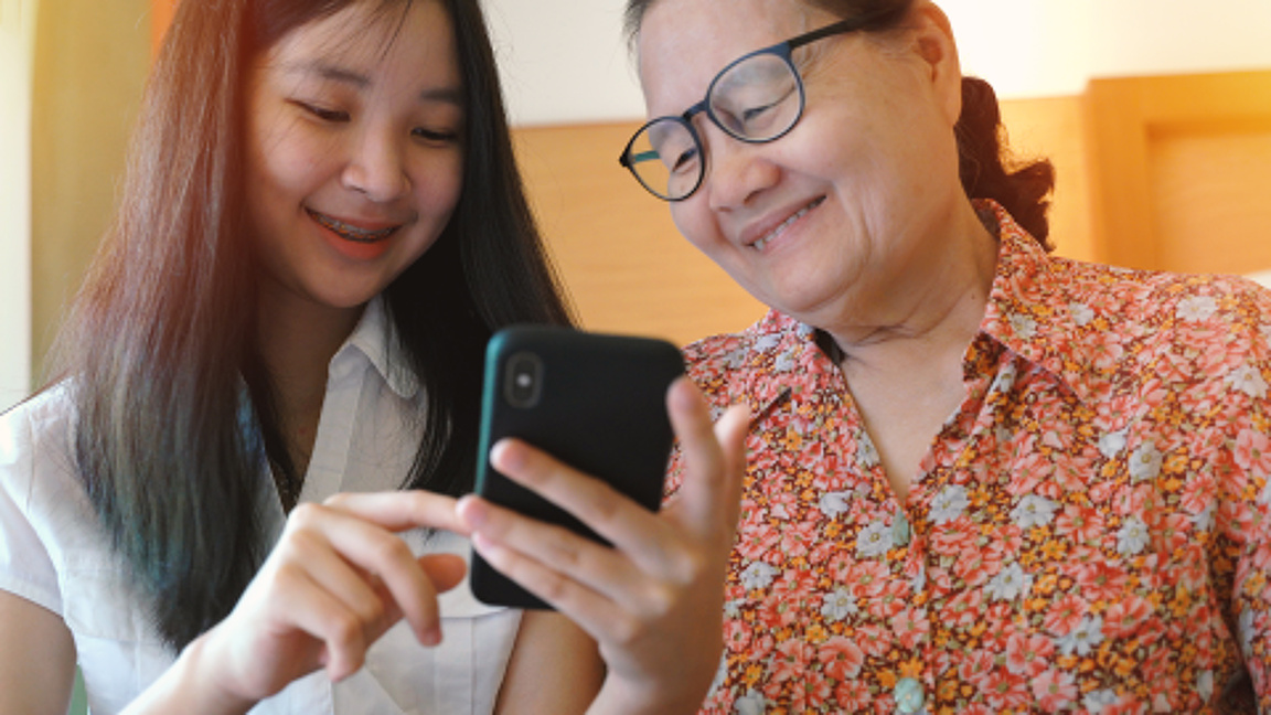 Young Teen Teaching Grandmother How to Use Smartphone